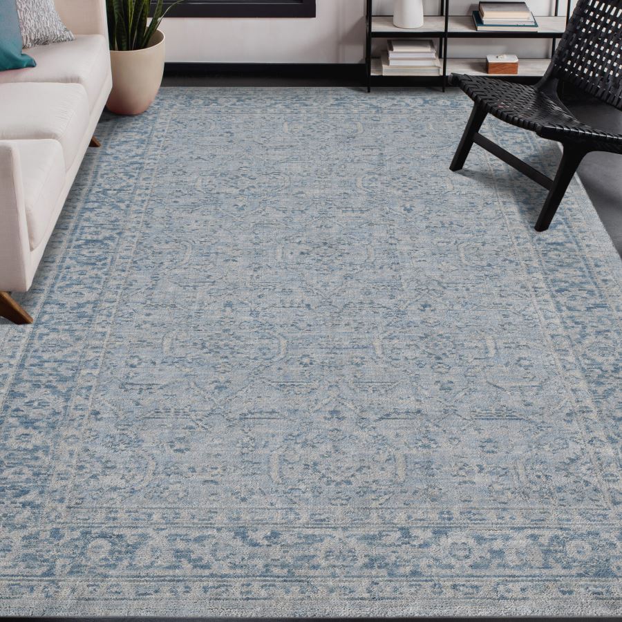Living room with a blue patterned rug, white sofa, and black chair.