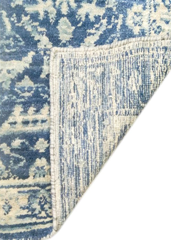 Blue and white patterned rug corner on a white background