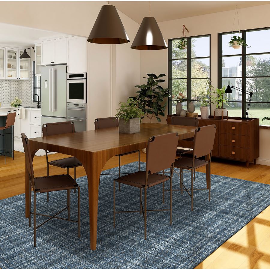 Dining area with wooden table and chairs on a blue rug in a modern kitchen.