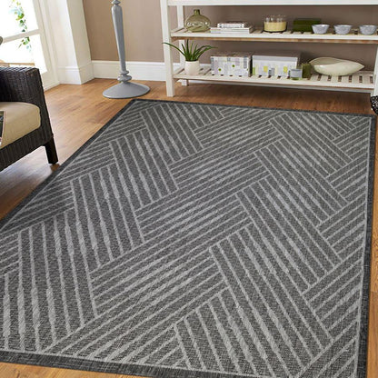 Gray geometric patterned rug on a wooden floor with a shelf in the background.