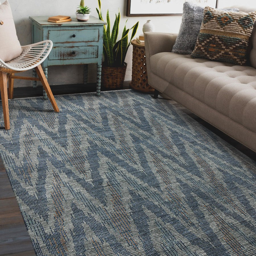 Living room with a blue patterned rug, beige sofa, and wooden chair.