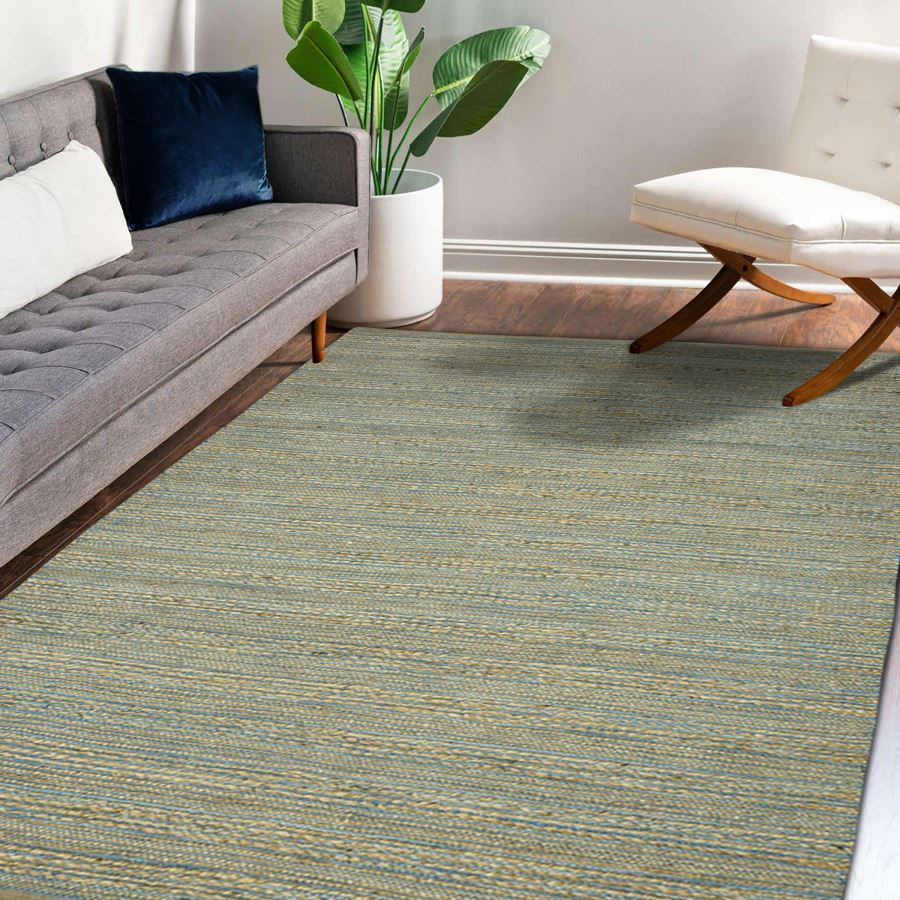 Living room with a gray sectional sofa, white ottoman, and green patterned rug.