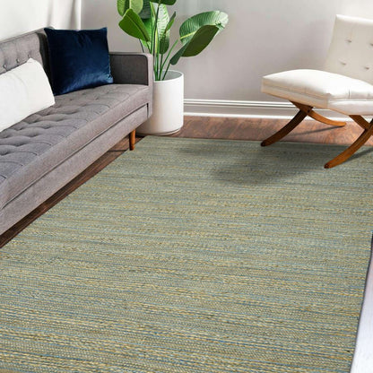 Living room with a gray sectional sofa, white ottoman, and green patterned rug.
