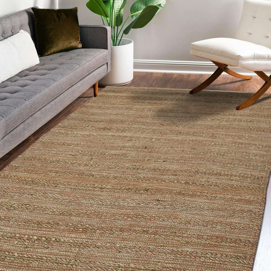 Living room with a brown textured rug, gray sofa, and white ottoman.