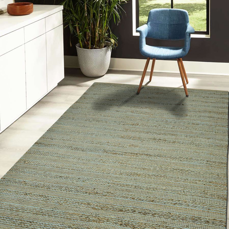 Green patterned rug in a room with a blue chair and a plant.