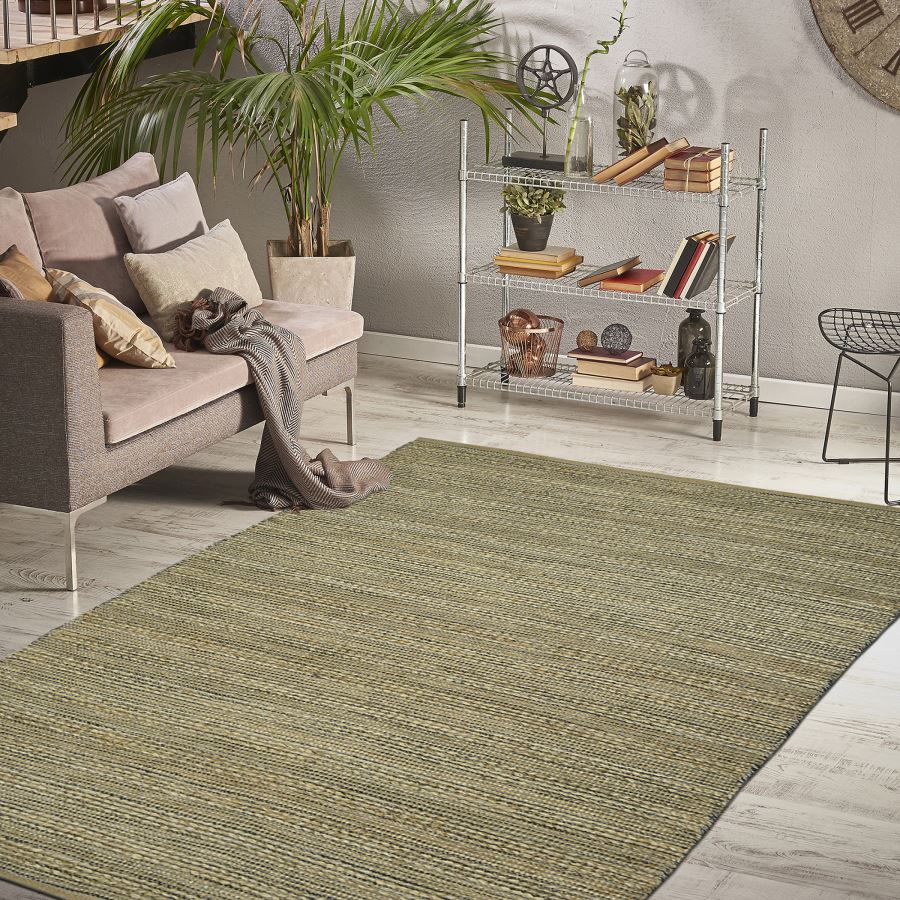 Living room with a green rug, sofa, and decorative items on a shelf.