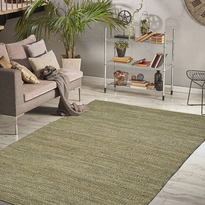 Living room with a green rug, sofa, and decorative items on a shelf.
