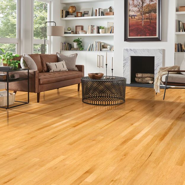 Living room with wooden flooring, brown sofa, and bookshelves.
