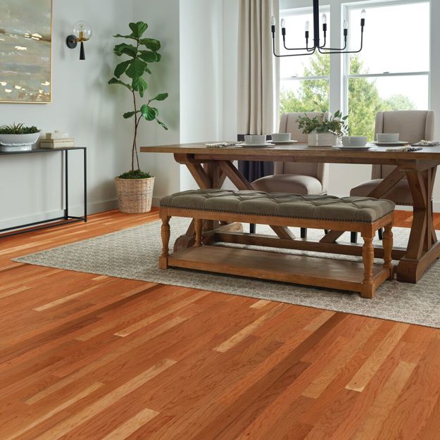 Dining room with wooden table and bench, plants, and large window.