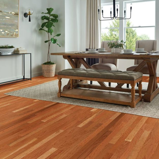 Dining room with wooden table and bench, plants, and large window.