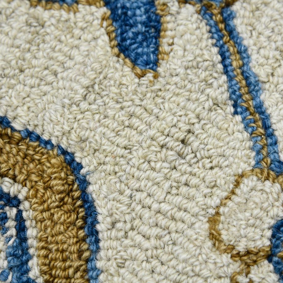 Close-up of a textured rug with geometric pattern in beige, blue, and brown.