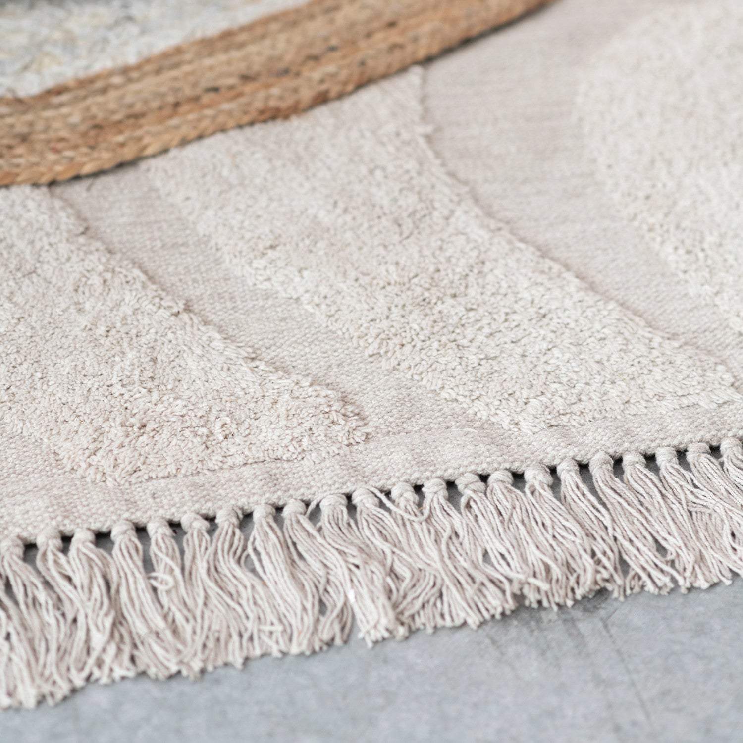 Close-up of a textured rug with fringes on a neutral background