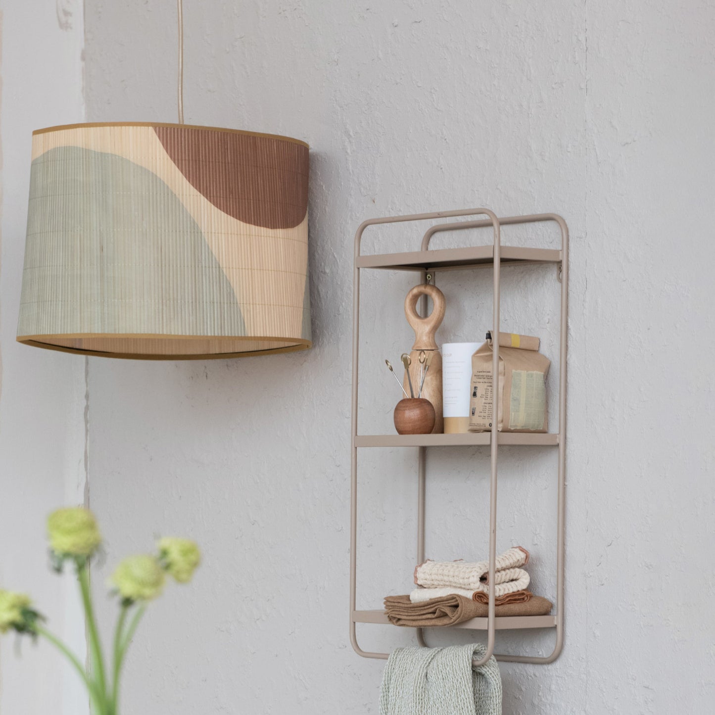 Wall-mounted shelf with decorative items and a lamp with a geometric shade on a light gray wall.