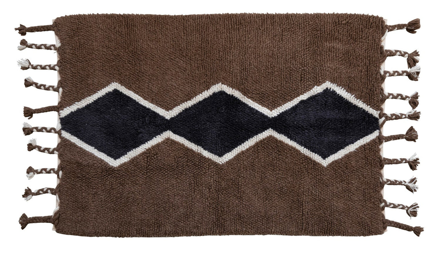 Woven rug with zigzag pattern and tassels on a white background