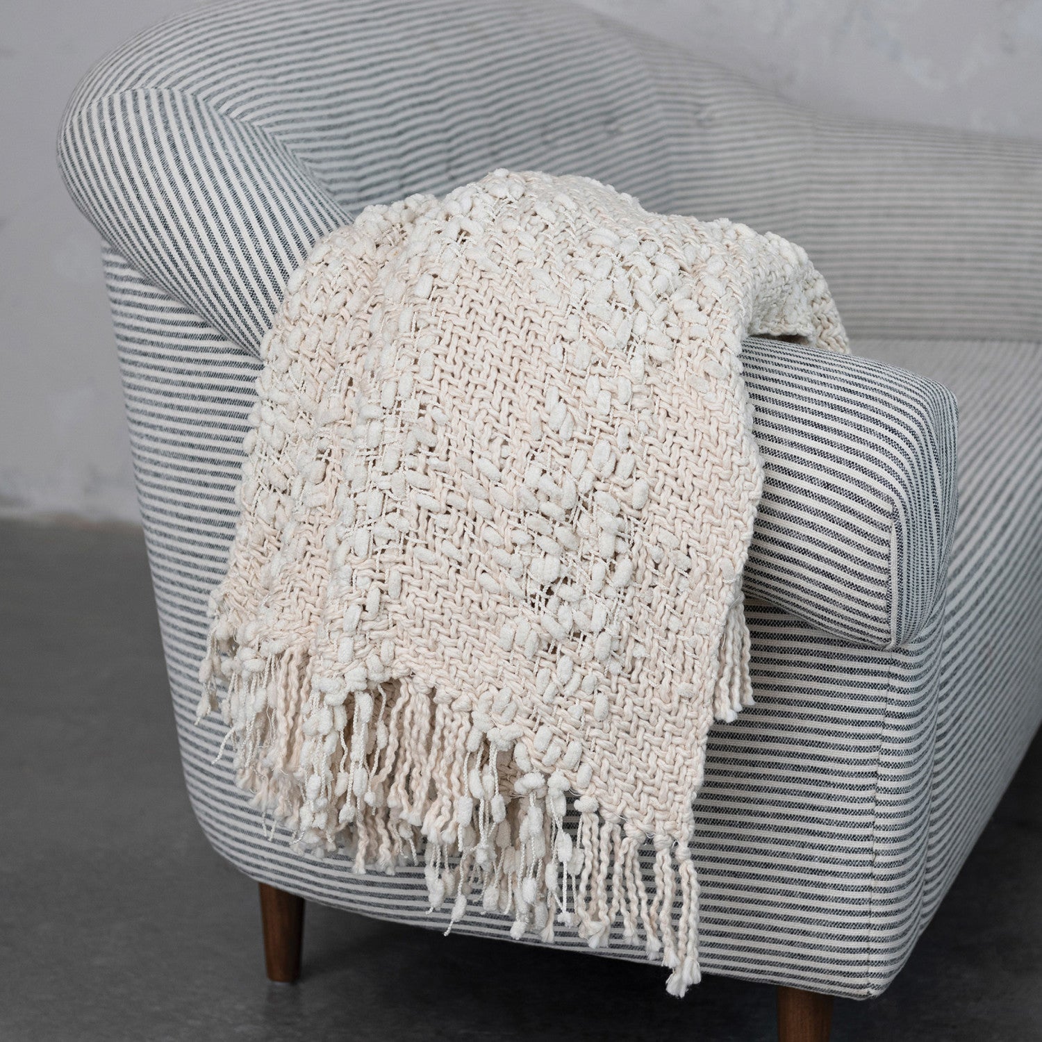 Textured blanket draped over a striped armchair