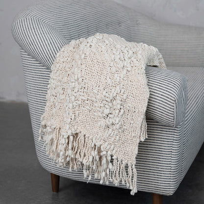 Textured blanket draped over a striped armchair