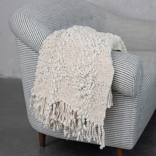 Textured blanket draped over a striped armchair