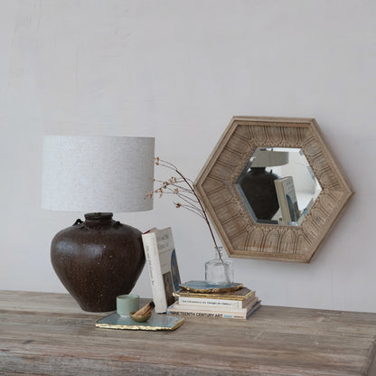 Decorative items on a wooden surface with a lamp, books, and a mirror.