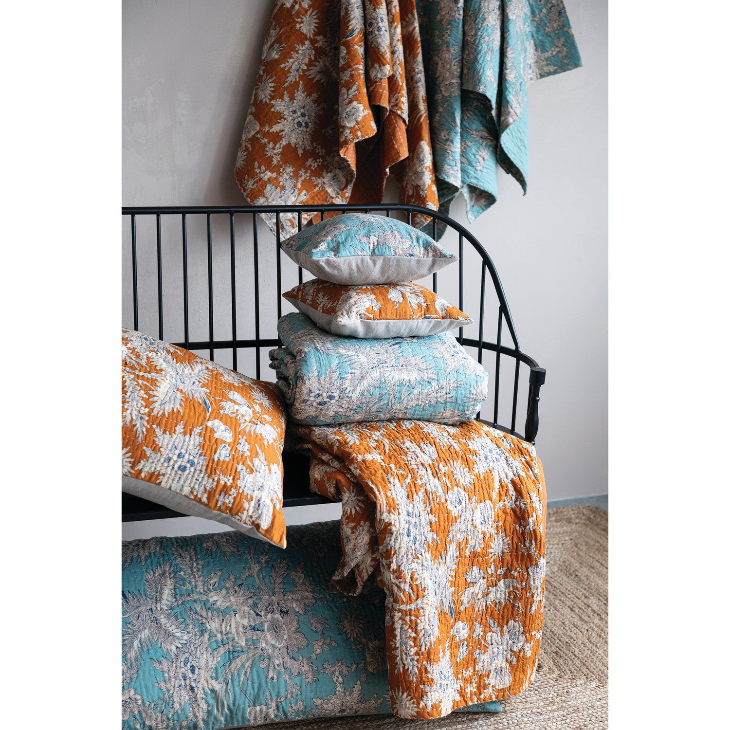 Bed with floral bedding and pillows in orange, blue, and white.