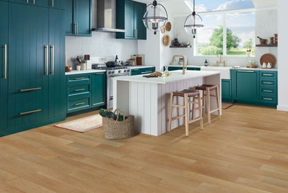 Modern kitchen with teal cabinets, white island, and wooden floor.