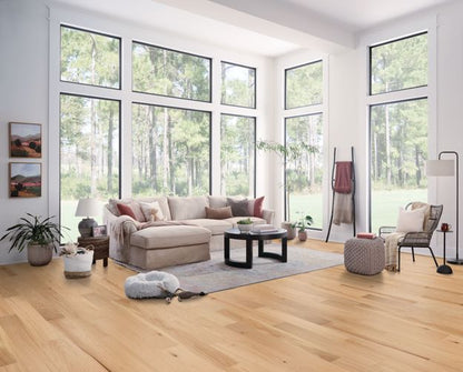 Modern living room with large windows, beige sectional sofa, and wooden flooring.