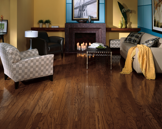 Living room with wooden floor, sofa, armchair, and fireplace.