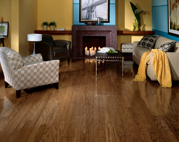 Living room with wooden floor, sofa, armchair, and fireplace.