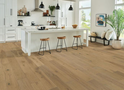 Modern kitchen with wooden flooring, white island, and bar stools.