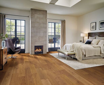 Modern bedroom with wooden flooring, fireplace, and large windows.