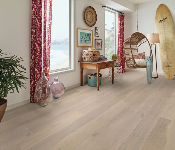 Modern living room with wooden flooring, decor items, and a view of water through large windows.