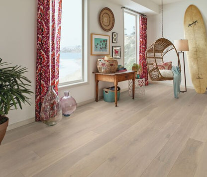 Modern living room with wooden flooring, decor items, and a view of water through large windows.