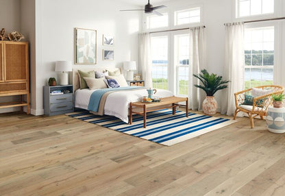Modern bedroom with wooden floor, striped rug, and large windows.