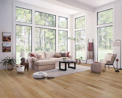 Modern living room with large windows, beige sectional sofa, and wooden flooring.