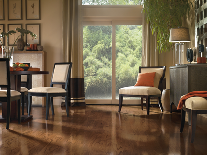 Living room with chairs, a table, and a large window showing greenery outside.